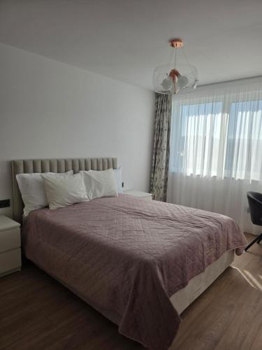 a bedroom with a large bed with a purple blanket at Zen aeroport confort in Sînnicoară