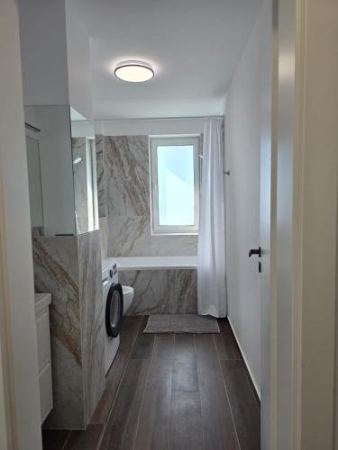 a bathroom with a tub and a toilet and a window at Zen aeroport confort in Sînnicoară