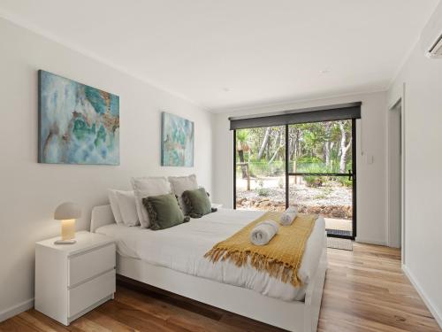 a white bedroom with a large bed and a window at Wren Studio - Private One-Bedroom Studio Nestled in Bushland in Yallingup