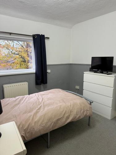 a bedroom with a bed and a television and a window at Bright Private Room with Parking & Garden Access in Spennymoor