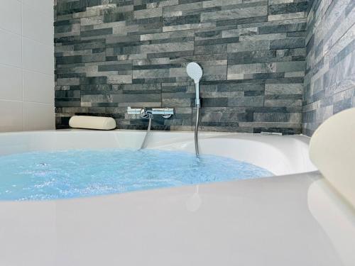 a bath tub filled with blue water in a bathroom at Wellness Suite Ponsardin 2 - Reims Centre in Reims