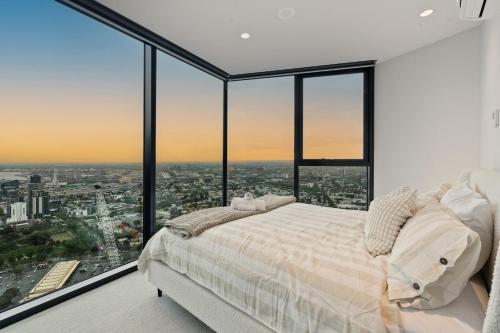 a bedroom with a large bed and large windows at Skyrise City Apartment with Pool Gym & Sauna in Melbourne