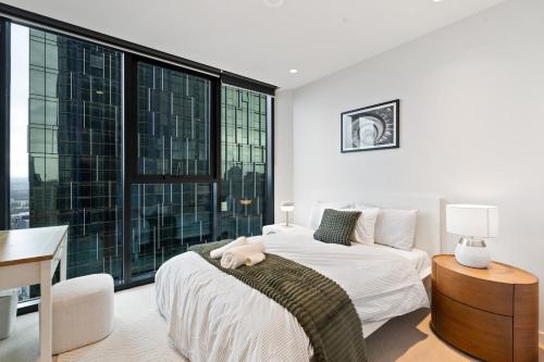 a bedroom with a bed and a desk and a large window at Skyrise City Apartment with Pool Gym & Sauna in Melbourne