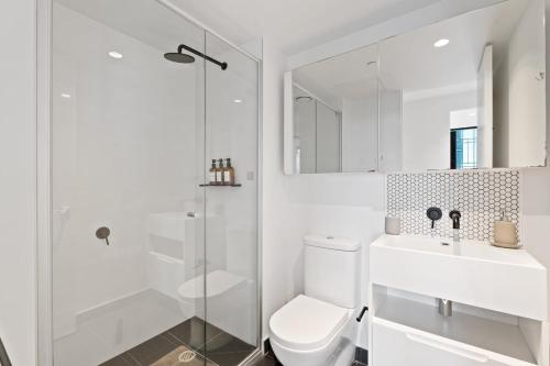 a white bathroom with a toilet and a shower at Skyrise City Apartment with Pool Gym & Sauna in Melbourne