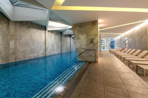 a swimming pool in a building with chairs at Skyrise City Apartment with Pool Gym & Sauna in Melbourne