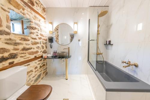 a bathroom with a stone wall and a tub and a sink at Αρχοντικό 1716 in Agios Lavrentios