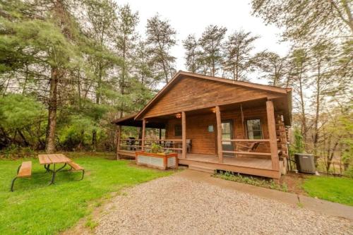 a cabin in the woods with a picnic table and a bench at Charming Log Cabin with a Fire Pit in the Woods near Lake Logan in Ohio in Cedar Grove