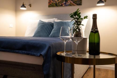a bed with a bottle of wine and two glasses on a table at Sette Vele Rooms in Trieste