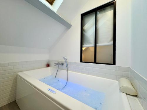a bathroom with a tub with blue water in it at Wellness Suite Ponsardin 3 - Reims Centre in Reims