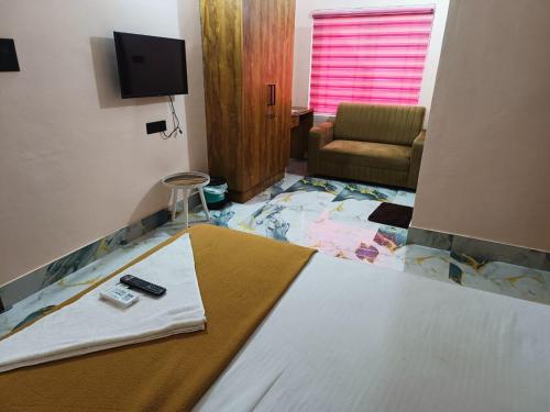 a bedroom with a bed with a television and a chair at Radhika Residency in Perintalmanna