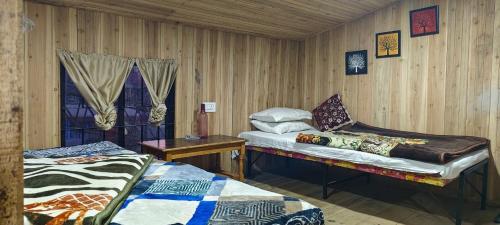 大吉岭Shubh Aagaman Homestay的有两张床、一张桌子和一扇窗户的房间