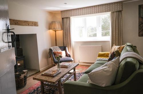 Apsley Cottage في Trotton: غرفة معيشة مع أريكة خضراء وطاولة قهوة