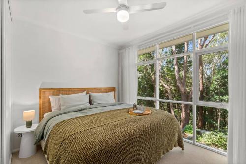 a bedroom with a bed and a large window at Forest Trails Escape - Bushland Serenity near Beach in Austinmer
