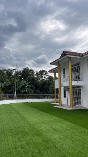 a white building with a large green field in front of it at Anggun's palace in Pasir Gudang