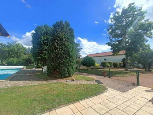 a yard with a large tree next to a swimming pool at L escapade de l'Ancien Rail in Pouilly-sous-Charlieu