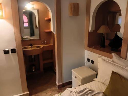 a bathroom with a sink and a bed and a mirror at Riad Le Bijou de Zahra Marrakech Kasbah in Marrakech