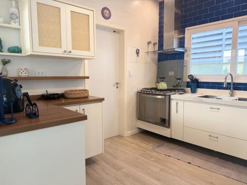 eine Küche mit weißen Schränken und einem Herd mit Backofen in der Unterkunft Refúgio em Juquehy no centro a poucos metros do mar com piscina privativa aquecida in São Sebastião