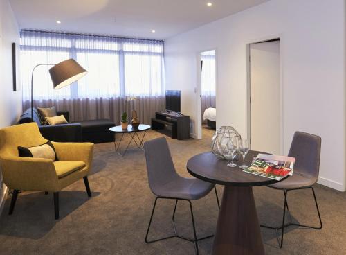 a living room with a couch and a table and chairs at Silkari Suites at Chatswood in Sydney