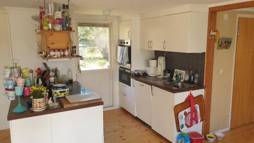 Una cocina con gabinetes blancos y encimera. en Spersboda 2 barnvänliga hus sjöutsikt & VARM pool Spersboda, en Spersboda