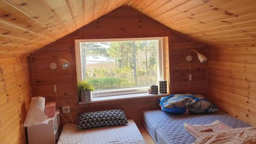 Habitación pequeña con ventana en una casa de madera en Spersboda 2 barnvänliga hus sjöutsikt & VARM pool Spersboda, en Spersboda