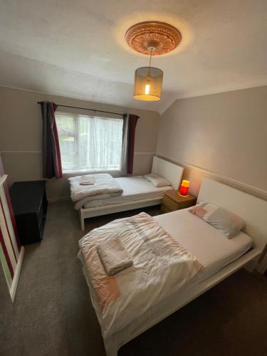 a bedroom with two beds and a window at Lovely 4 bed house with patio & bbq in Slades Green