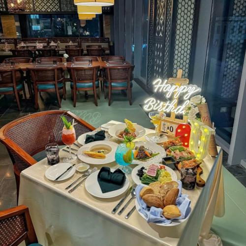 een tafel met borden vol eten en een bord met 'Happy Birthday' bij Panorama Sky Beach Recidences in Nha Trang
