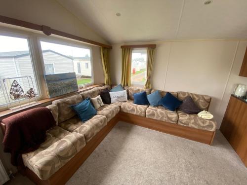 ein Wohnzimmer mit einer großen Couch mit blauen Kissen in der Unterkunft Lovely 6 Berth Caravan Nearby Hunstanton Beach In Norfolk Ref 23020T in Hunstanton