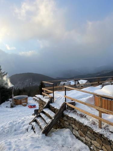 een met sneeuw bedekte helling met een houten hek en een trap bij Pensiunea Casa Ancutei in Ranca