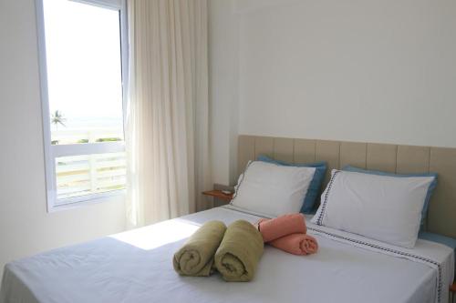 a bedroom with two towels on a bed with a window at Apartamento Vista Mar atalaia varanda gourmet in Aracaju