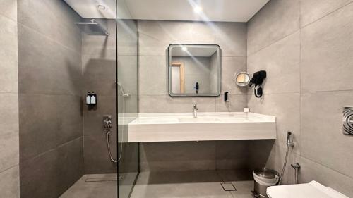 a bathroom with a sink and a glass shower at Grand Continental Hotel in Abu Dhabi