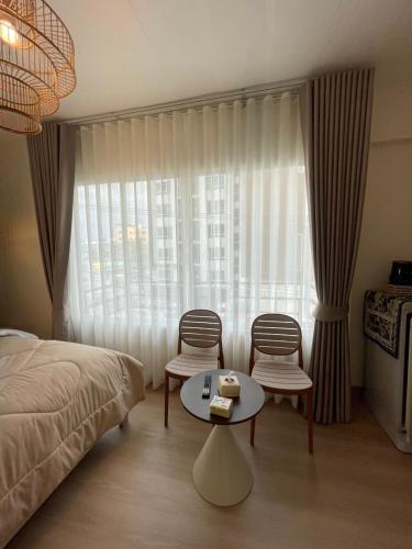 a bedroom with a bed and two chairs and a table at Mari Home in Bangsaen