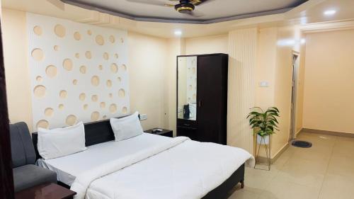 a bedroom with a large white bed and a plant at Hotel jain palace in Chhatarpur