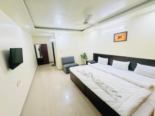 a bedroom with a large bed and a chair at Hotel jain palace in Chhatarpur