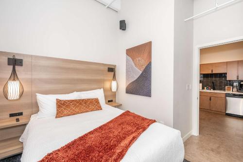 a bedroom with a large white bed and a kitchen at The 333 Suites 202 - Stay for 6 in Cincinnati