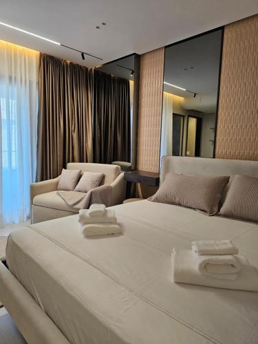 Un dormitorio con una gran cama blanca y un sofá. en Imperial Suites Vlora, en Vlorë