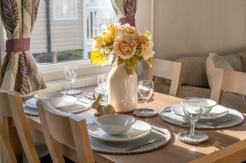 uma mesa de jantar com um vaso de flores sobre ela em Vacant Nests Aberlady Seton Sands em Port Seton