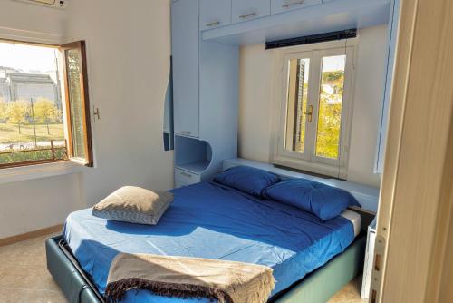 1 Schlafzimmer mit einem Bett mit blauer Bettwäsche und 2 Fenstern in der Unterkunft lakefront and parking - Lakefront Escape in Desenzano del Garda