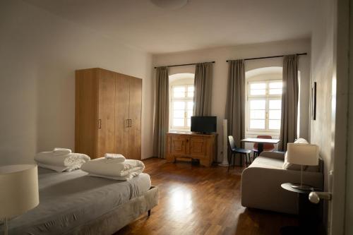 a bedroom with two beds and a desk and a television at Residence Fink Central Apartments in Bolzano