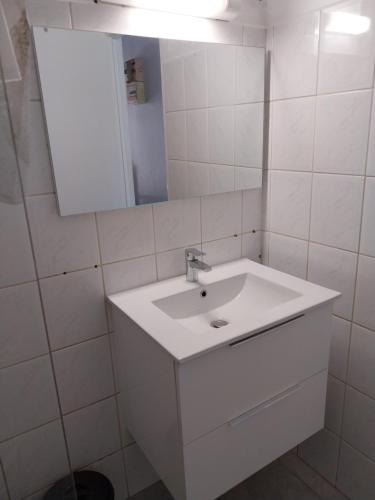 Un baño blanco con lavabo y espejo. en Chez Rosalie, en Lamentin