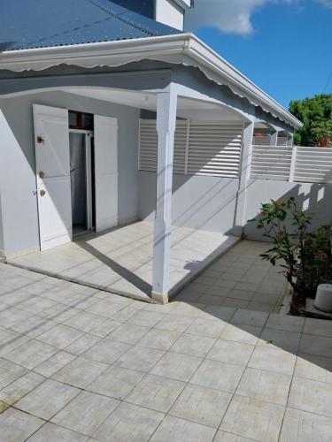 a white garage with a roof and a patio at Chez Rosalie in Lamentin