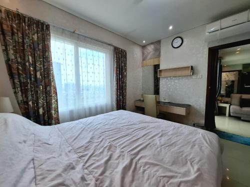 - une chambre avec un lit, un bureau et une horloge dans l'établissement THAMRIN RESIDENCE APARTMENT luxurious 1 BEDROOM FLAT SCBD beside GRAND INDONESIA mall, à Jakarta