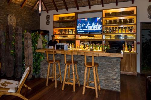 a bar with stools and a tv on the wall at Residence Alizees Spa in Mauritius