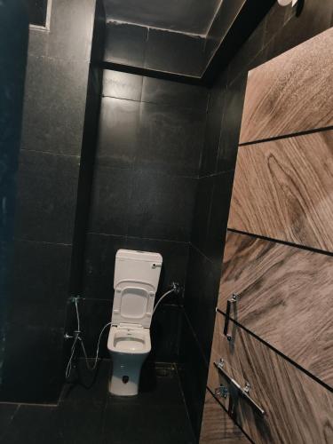 a bathroom with a toilet in a black wall at Shivay Adventure in Kevadia