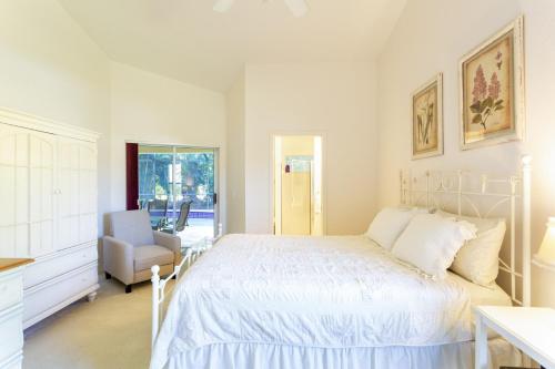 Un dormitorio blanco con una cama y una silla. en SERENE & ATTRACTIVE 3BR HEATED POOL/SPA HOME, en Estero