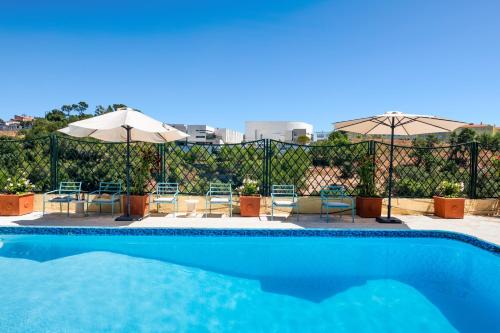 a swimming pool with tables and chairs and umbrellas at MBird 19 Estoril Apartments 203 in Estoril