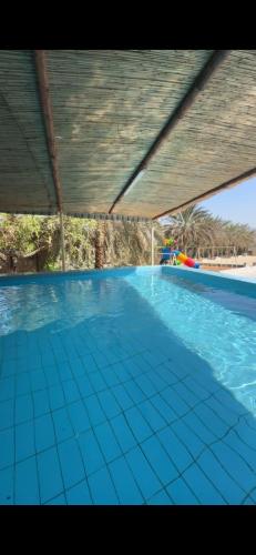 Una gran piscina con azulejos azules en el suelo. en Crestora farm, en Ras al Khaimah