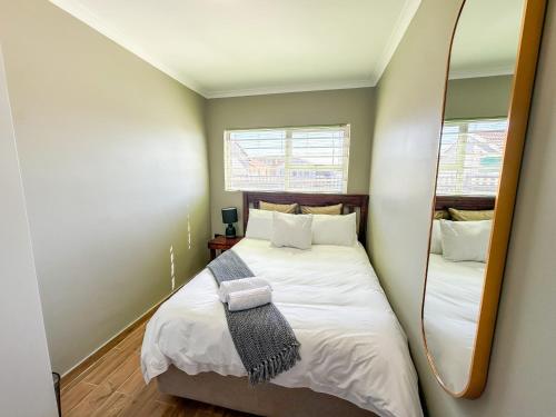 a small bedroom with a bed and a mirror at 29 Windsor Flatlet 2 in Silver Sands