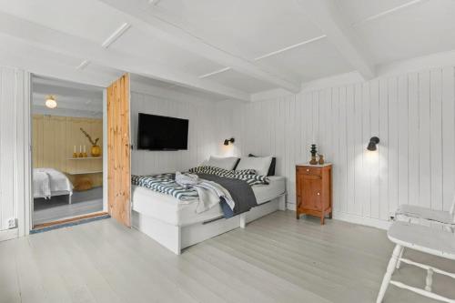 a white bedroom with a bed and a television at 200-Year-Old House By The Southern Archipelago in Mandal