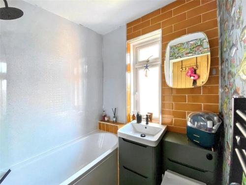 a bathroom with a bath tub and a sink at Drew Street Digs in Brixham
