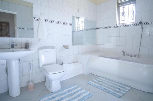 une salle de bain blanche avec toilettes et lavabo dans l'établissement Tara Villa - Elegant 4-Bedroom Home in Buziga - Kampala, à Kampala